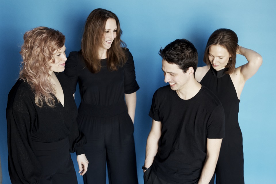 Group photo of the quartet on blue wall